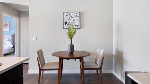 Un coin repas avec une table ronde en bois, deux chaises et un vase contenant des plantes vertes.