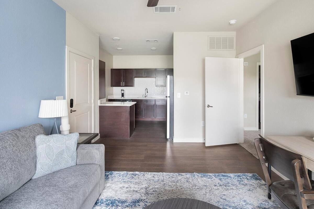 A modern apartment with a living room, kitchenette, and a dining area.