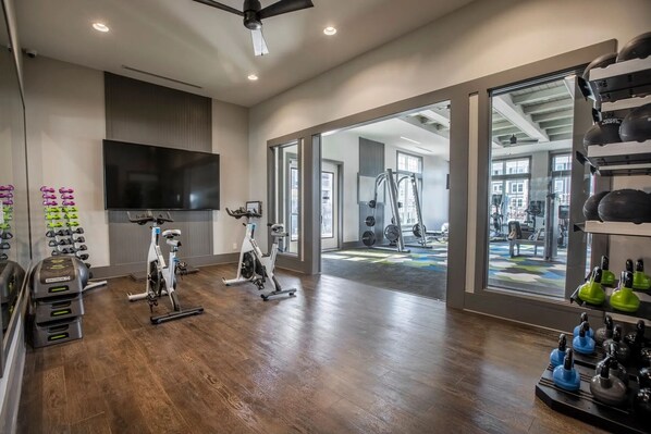 A spacious home gym with exercise bikes, a TV, and weightlifting equipment. - Landing Apartments Murfreesboro near Fairfield Estates (Murfreesboro)