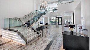 A spacious lobby with a modern staircase, a reception desk, and a view of the outdoors. - Landing Apartments Orlando - Central Business District (Orlando)