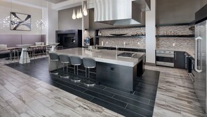 A modern kitchen with a central island, bar stools, a built-in oven, and a large window. - Landing Apartments Orlando - Central Business District (Orlando)