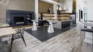 A modern kitchen with a central island, bar stools, and a dining area with a table and chairs. - Landing Apartments Orlando - Central Business District (Orlando)