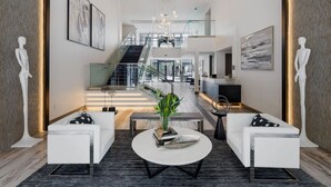 A modern interior with white sofas, a round coffee table with a plant, and a staircase leading to an upper level. - Landing Apartments Orlando - Central Business District (Orlando)