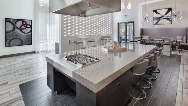 A modern kitchen with a central island, bar stools, and a dining area with a bench and chairs. - Landing Apartments Orlando - Central Business District (Orlando)