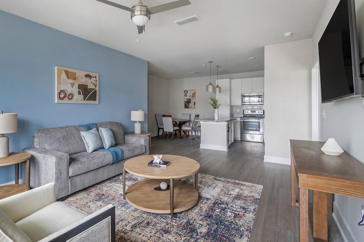 Ein modernes Wohnzimmer mit grauem Sofa, rundem Couchtisch und einer blauen Akzentwand.