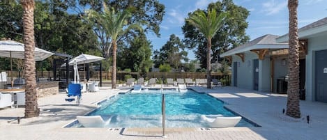 A rectangular swimming pool with two lanes, surrounded by lounge chairs and palm trees.