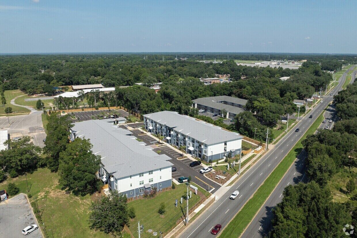 An aerial view of a commercial building complex with multiple parking lots and a main road.