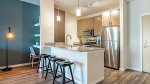 A modern kitchen with a central island, stainless steel appliances, and bar stools.