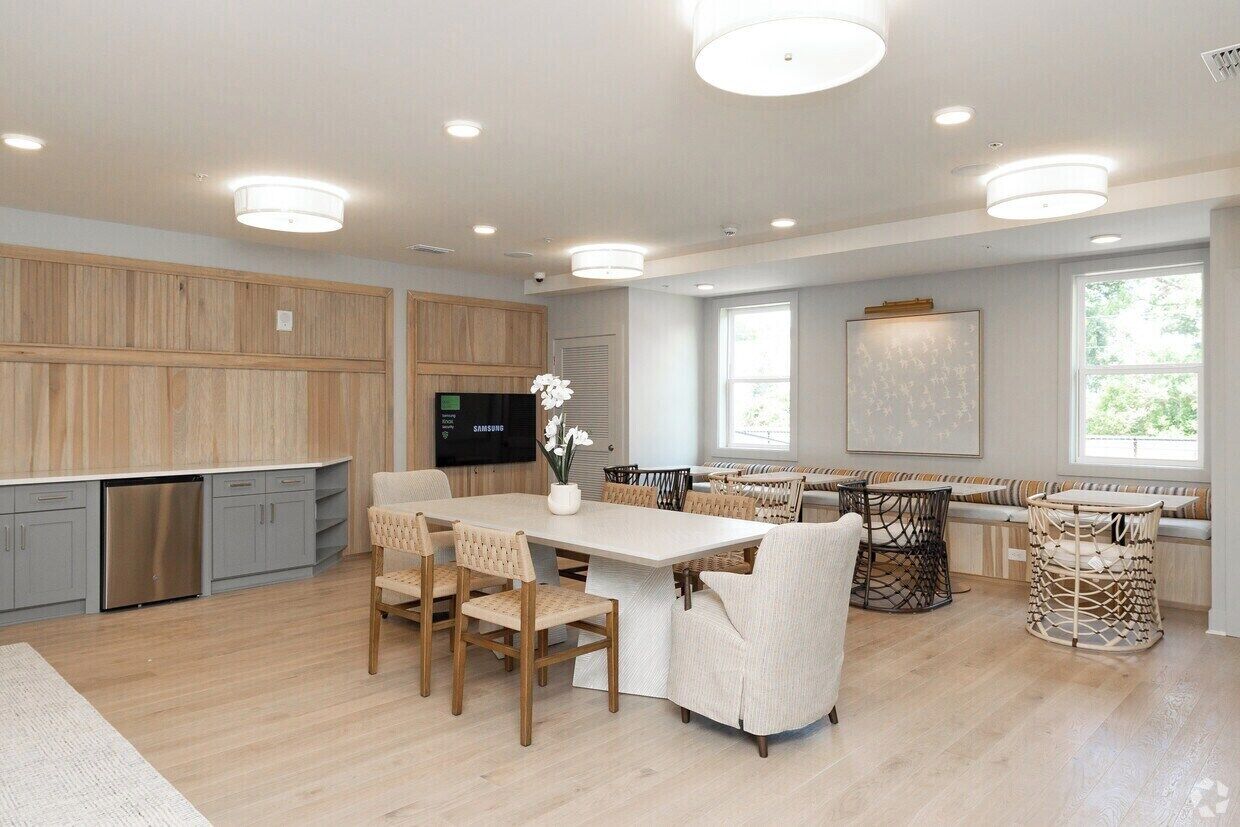 A modern kitchen with wooden cabinetry, a dining area with a large table and chairs, and a built-in TV.