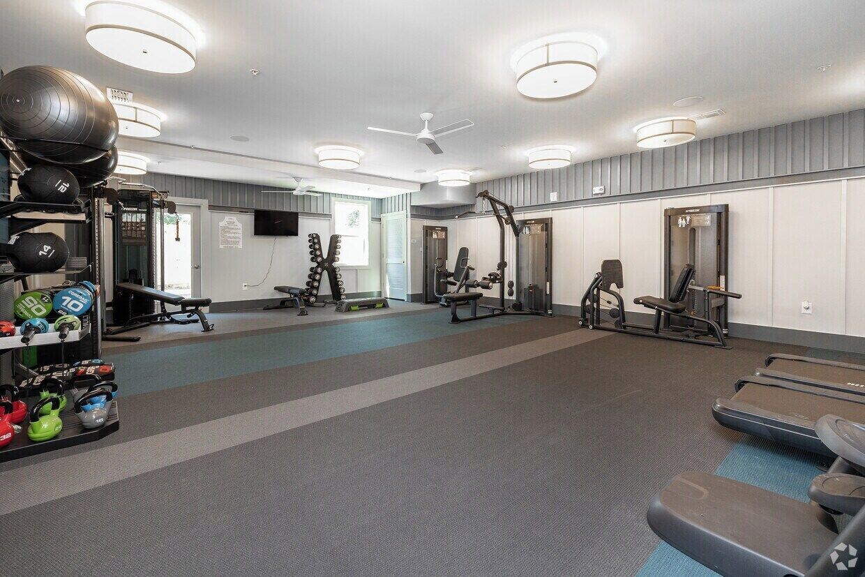 Ein Fitnessstudio mit Trainingsgeräten, Laufbändern und Kurzhanteln.