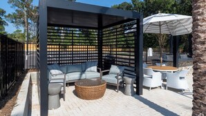 A covered outdoor seating area with a sofa, chairs, and a round table.