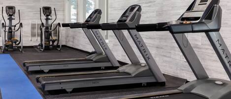 A row of treadmills labeled "MATRIX" in a gym with a blue mat and white walls.