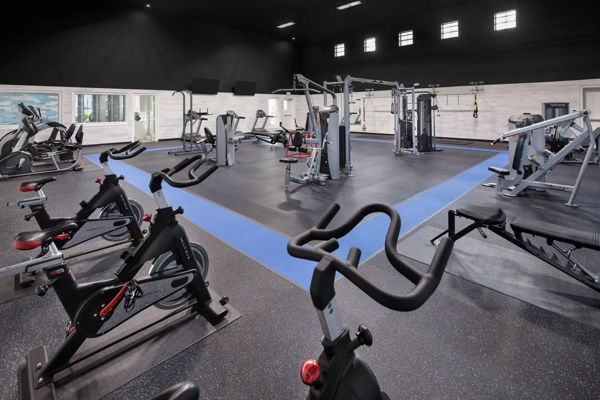A gym with various exercise equipment, including treadmills, stationary bikes, and weight machines.