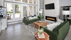 A modern living room with a green sofa, a coffee table, and a fireplace. - Landing Apartments Jacksonville - Windy Hill (Jacksonville)