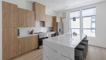 Una cocina moderna con armarios de madera, una isla de mármol y un ventanal que proporciona luz natural.