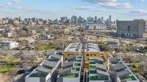 Um moderno complexo de apartamentos com um pátio central, rodeado por um horizonte urbano.