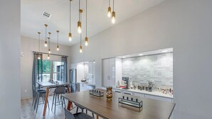 Una cocina moderna con una isla grande, electrodomésticos integrados e iluminación colgante.