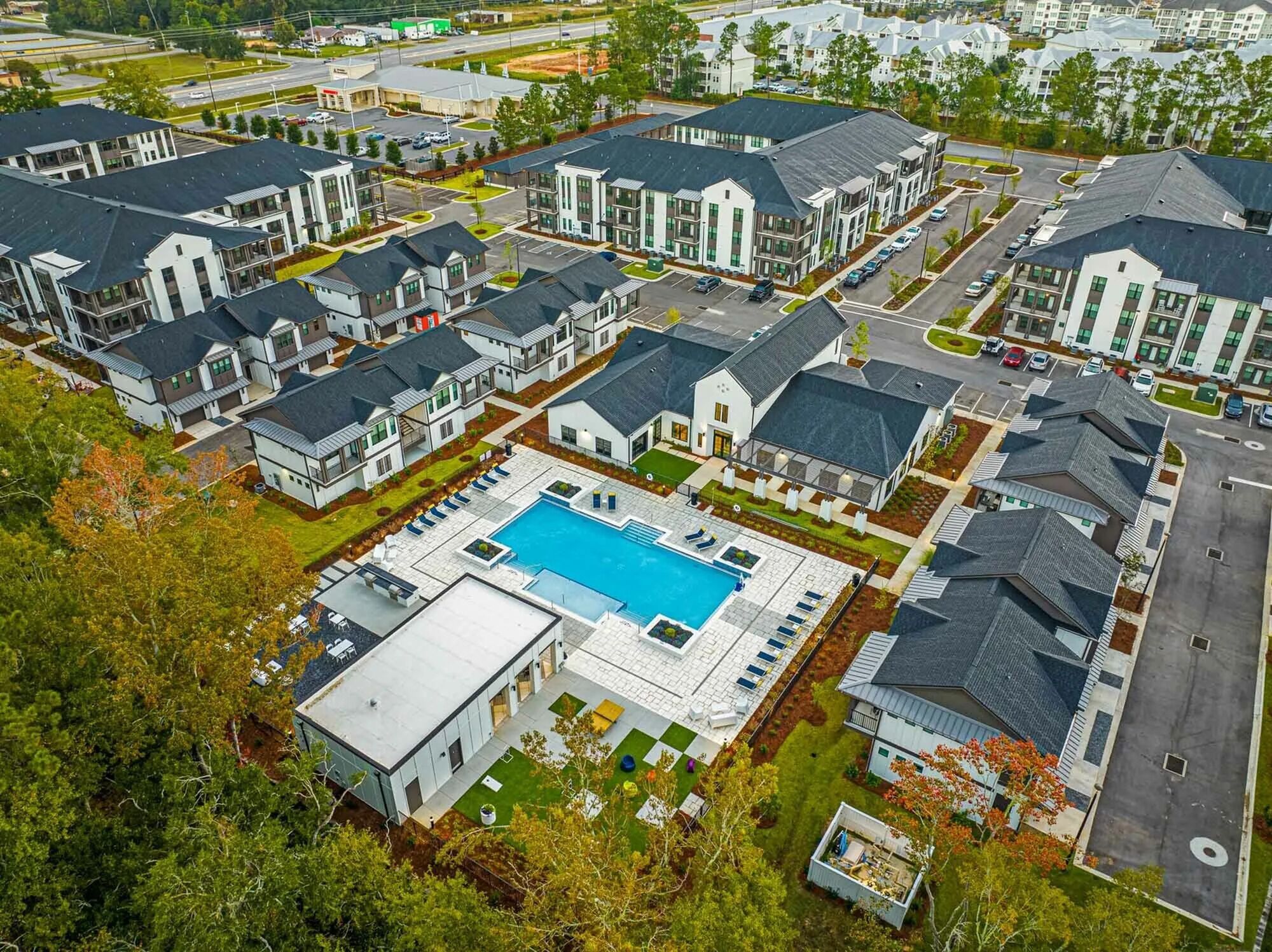 A residential complex with modern architecture, a central swimming pool, and well-maintained lawns.