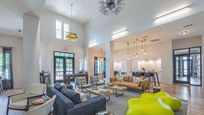 Amplia sala de estar con un sofá, sillones, una mesita de centro y un sillón de felpa verde brillante.