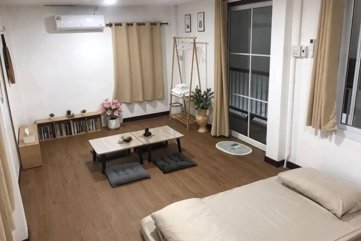 Una habitación con una cama, una mesa con un jarrón, un columpio y vistas al exterior.