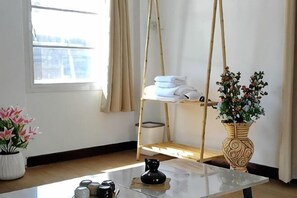 Una habitación con una silla colgante, un estante con toallas, un jarrón con flores y una mesa con una tetera.