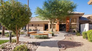 A modern building with a patio area, outdoor seating, and a well-maintained garden.