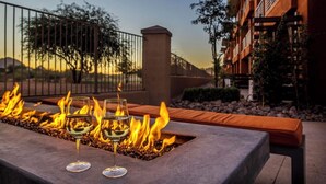 A fire feature with two glasses of wine on a patio.