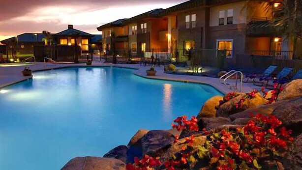 A swimming pool surrounded by lounge chairs and a building with multiple windows.