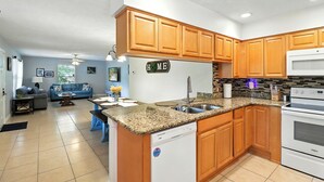 Una cucina moderna con mobili in legno, un piano di lavoro in granito, lavastoviglie integrata e forno a microonde.