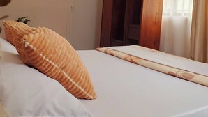 Une chambre à coucher avec un lit, une armoire, une fenêtre avec des rideaux et une plante.