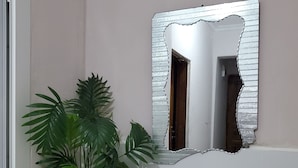 Une salle de bain avec un lavabo blanc, un miroir doté d’un cadre décoratif et une plante en pot.