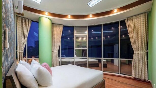 A bedroom with a bed, a large window, and a view of the night sky. - An Corner - My Vinh Apartment - Central D3 (Ho Chi Minh City)