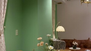 A room with a green wall, a brown leather sofa, a small round table, and a lamp. - An Corner - My Vinh Apartment - Central D3 (Ho Chi Minh City)