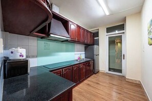 A kitchen with wooden cabinets, a black countertop, and a built-in oven. - An Corner - My Vinh Apartment - Central D3 (Ho Chi Minh City)