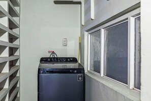 A compact room with a washing machine, a window with blinds, and a power outlet on the wall. - An Corner - My Vinh Apartment - Central D3 (Ho Chi Minh City)