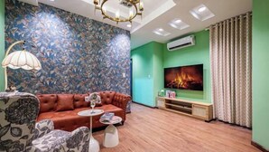 A living room with a sofa, a coffee table, a TV, and a floral wall. - An Corner - My Vinh Apartment - Central D3 (Ho Chi Minh City)