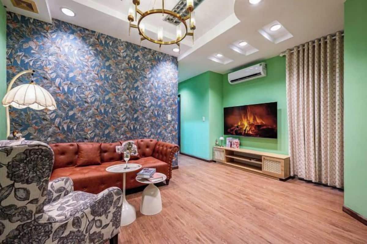 Ein Wohnzimmer mit einer Couch, einem Couchtisch, einem Fernseher und einer blumigen Wand.