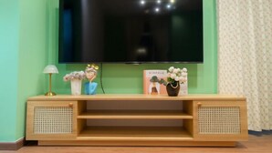 A flat-screen TV mounted on a wall above a wooden console table with decorative items. - An Corner - My Vinh Apartment - Central D3 (Ho Chi Minh City)