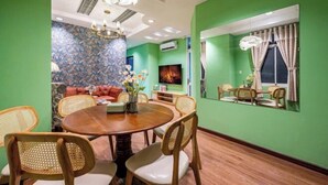 A dining area with a round wooden table, wicker chairs, and a green wall. - An Corner - My Vinh Apartment - Central D3 (Ho Chi Minh City)