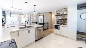 A modern kitchen with white cabinetry, stainless steel appliances, and pendant lighting. - Streamlined apartment with 2 free parking spaces. (Drummondville)