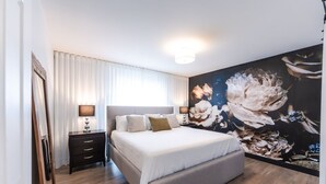 A bedroom with a large bed, a nightstand, a dresser, and a wall mural. - Streamlined apartment with 2 free parking spaces. (Drummondville)