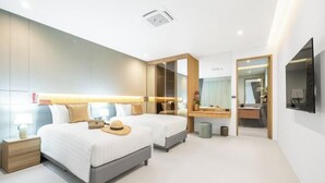 Una habitación de hotel moderna con dos camas, un espejo grande, un tocador y una televisión.