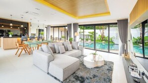 Una sala de estar moderna con un sofá seccional, comedor y vista a una piscina.