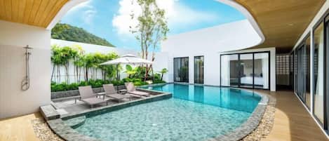 Una piscina interior moderna con agua cristalina, rodeada por un suelo de madera y un borde de piedra.