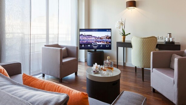 Una sala de estar moderna con televisor de pantalla plana, asientos cómodos, una mesa de centro y una orquídea en maceta.