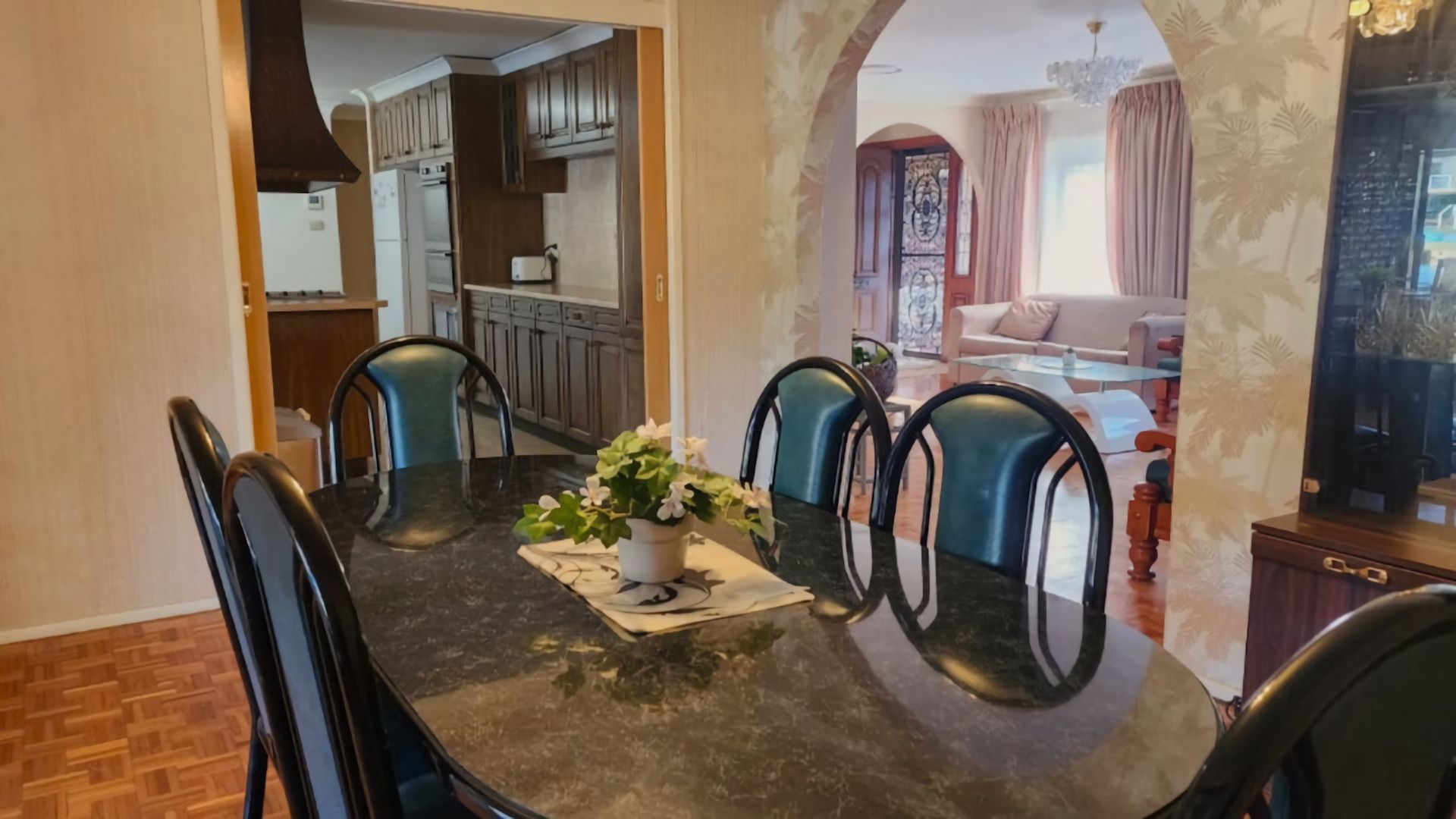 A dining area with a marble table, chairs, and a potted plant.