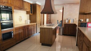 Eine Küche mit Holzausstattung, einer zentralen Kochinsel und integrierten Geräten, darunter eine Mikrowelle und ein Backofen.