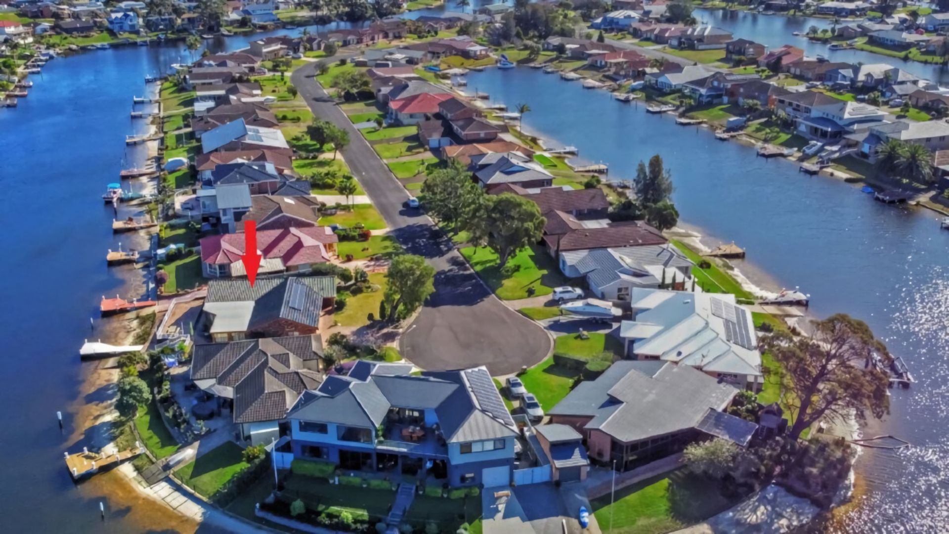 Un quartier résidentiel bordé de maisons le long d’une voie d’eau, avec une rue principale et une étendue d’eau.