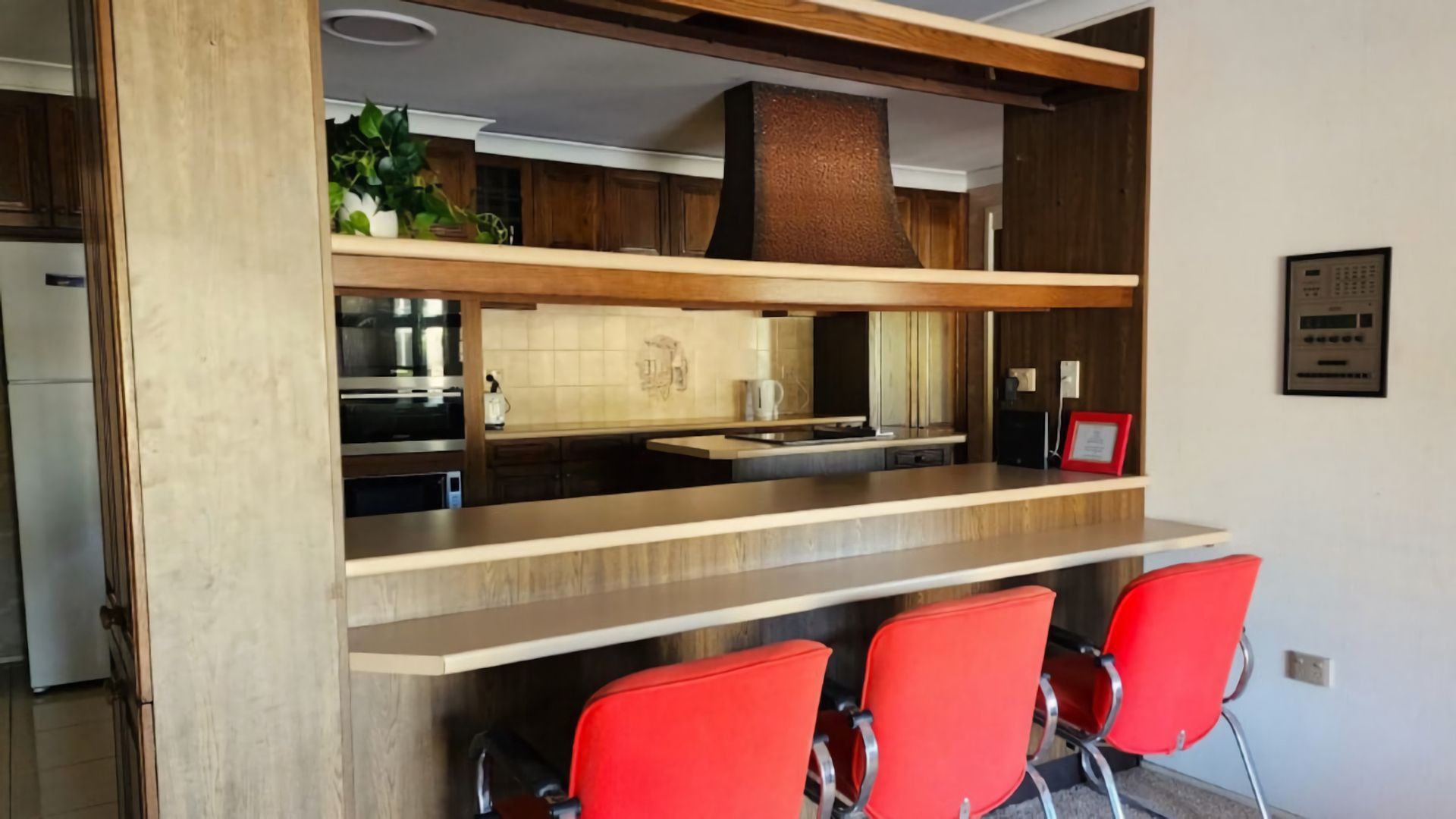 Una cocina moderna con una isla integrada, electrodomésticos de acero inoxidable y sillas rojas.