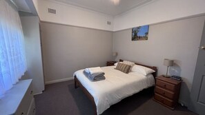 A hotel room with a bed, bedside tables, a lamp, and a painting on the wall.